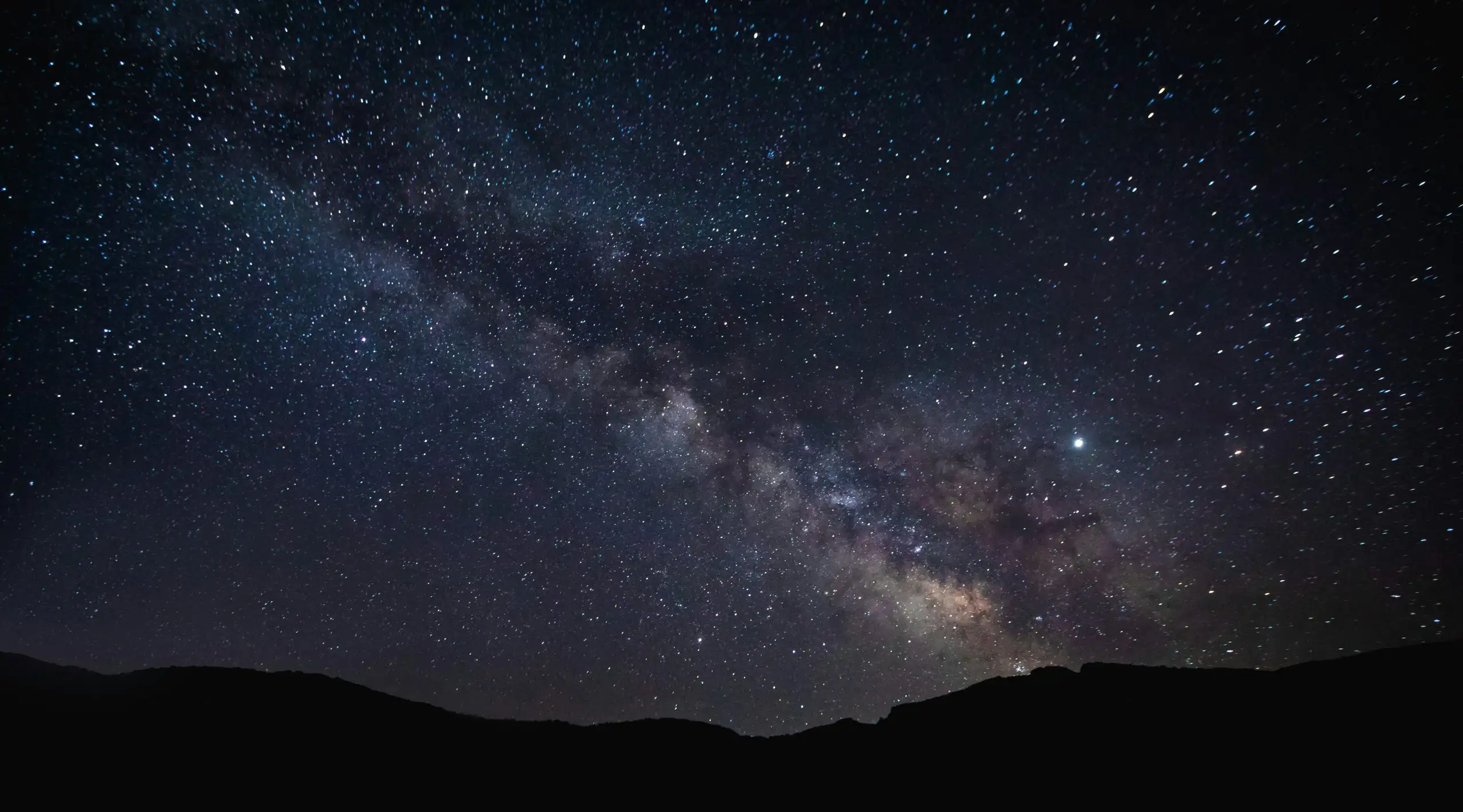 Starlit destination sky over quiet mountain silhouettes